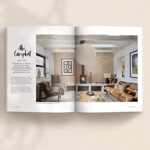 Open pages of 91 Magazine Issue 18 featuring Abi Campbell's home, with a cosy living room, wood-burning stove, large paper pendant light and vintage furniture.
