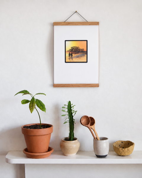 Brighton West Pier fine art print displayed on a wall with plants and handmade homeware