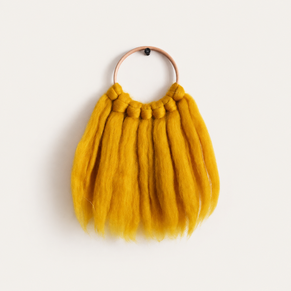 Handmade mustard yellow merino wool wall hanging by Suzanne Gattrell Hodshon, featuring soft wool fibres suspended from a natural wooden hoop.