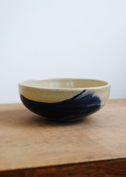 Angled view of a small ceramic bowl with white and cobalt glaze