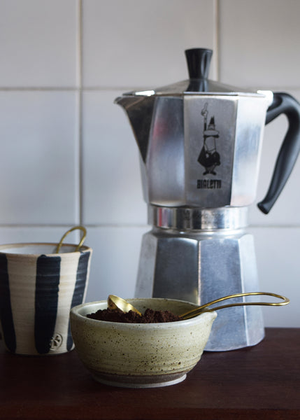 Brass and silver coffee scoop used to measure ground coffee for an espresso machine