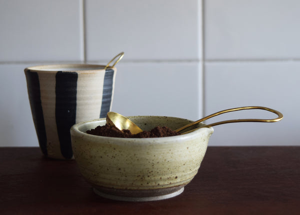 Brass and silver coffee scoop with ground coffee