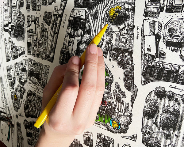 Person colouring the hand-drawn Brighton Map poster with coloured pencils