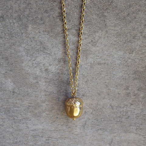 Gold acorn necklace by Alice Stewart Jewellery, handcrafted from sterling silver with 18k gold plating on a natural wood surface
