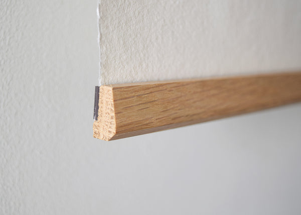 Close-up of the solid oak picture and poster hanger showing the natural wood grain