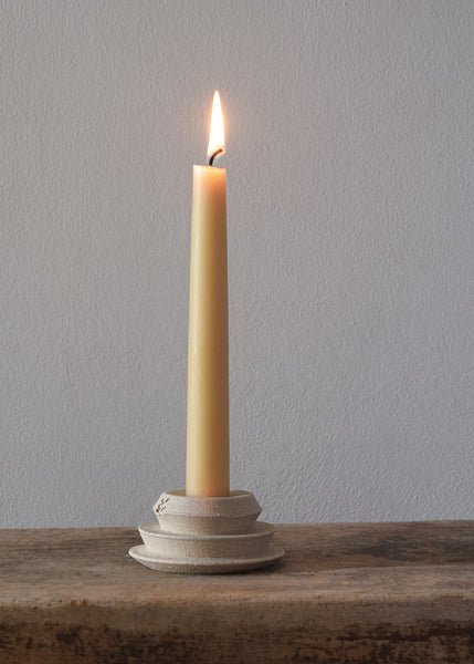 Stoneware candle holder with a lit beeswax dinner candle